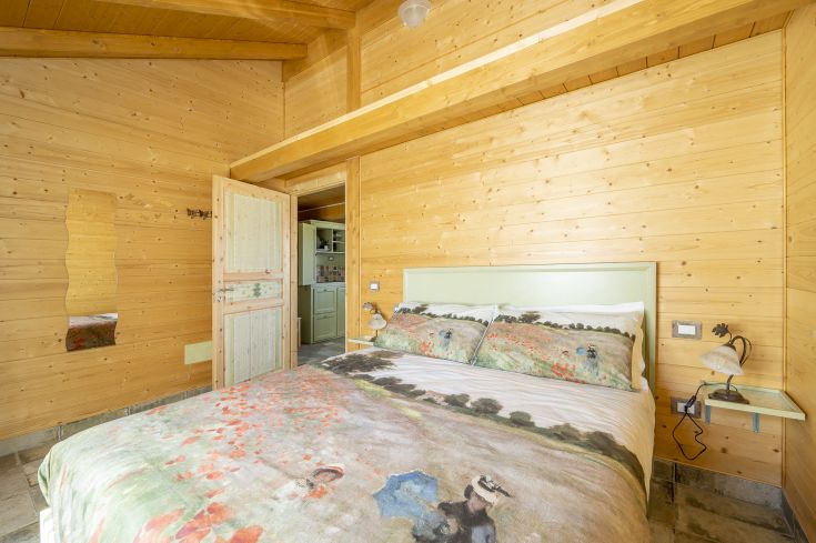 Une chambre en bois confortable avec une literie aux tons doux, parfaite pour un moment de détente.