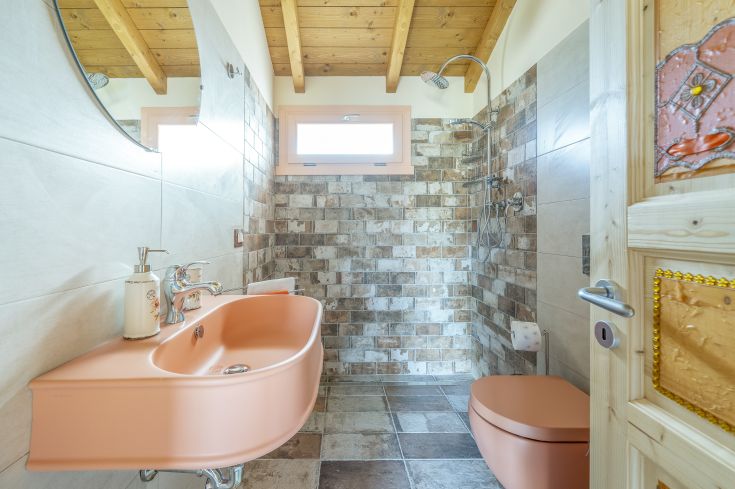 Salle de bain rénovée avec des carreaux de pierre clairs et un sol en céramique foncé, avec des détails dans des tons neutres.