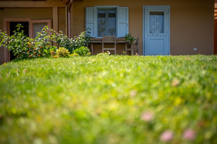 Une maison entourée d'arbres et de plantes, avec une table extérieure et des fleurs qui rendent l'environnement serein.