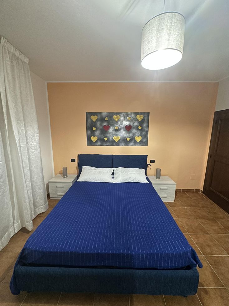 Camera matrimoniale semplice con decorazioni sobrie e un letto ben sistemato.