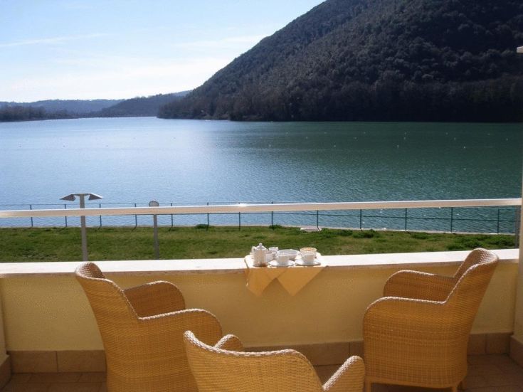 A balcony with comfortable chairs and a table overlooking Lake Piediluco.