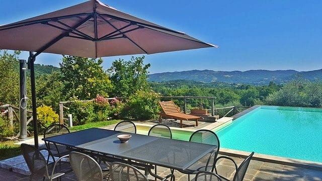 Großer Außenbereich mit Pool, Esstisch und Panoramablick auf die umliegende Natur.