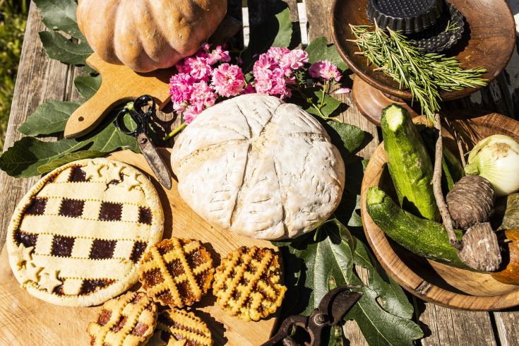 Un tavolo apparecchiato con piatti semplici, ortaggi freschi e qualche decorazione floreale. Un richiamo ai sapori tradizionali.