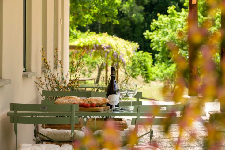 An outdoor table set with wine, bread, and fresh cherry tomatoes.