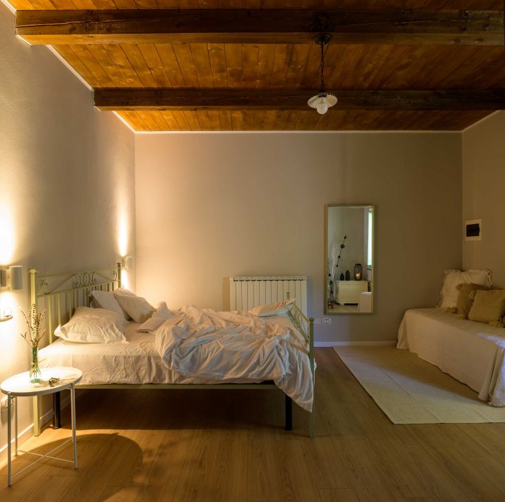 A cozy living room in a farmhouse, featuring simply arranged beds and soft lighting.