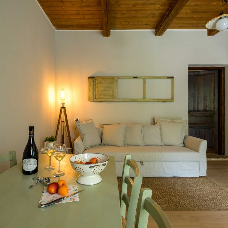 A simple living room with a couch, a table, fresh fruit, and a bottle of wine, perfect for relaxation.