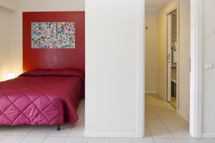 Une chambre simple avec un lit double, décorée dans des tons pastel, offrant une ambiance fonctionnelle et accueillante.