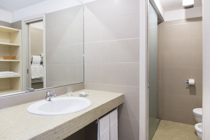 Une salle de bain simple et fonctionnelle, équipée d'un lavabo, d'un miroir et d'une douche.