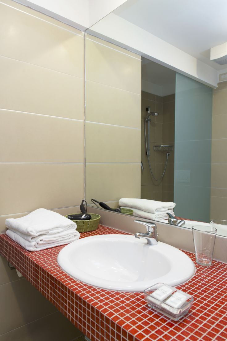 Une salle de bain moderne et lumineuse, avec lavabo, serviettes et douche séparée, décorée de manière simple et accueillante.