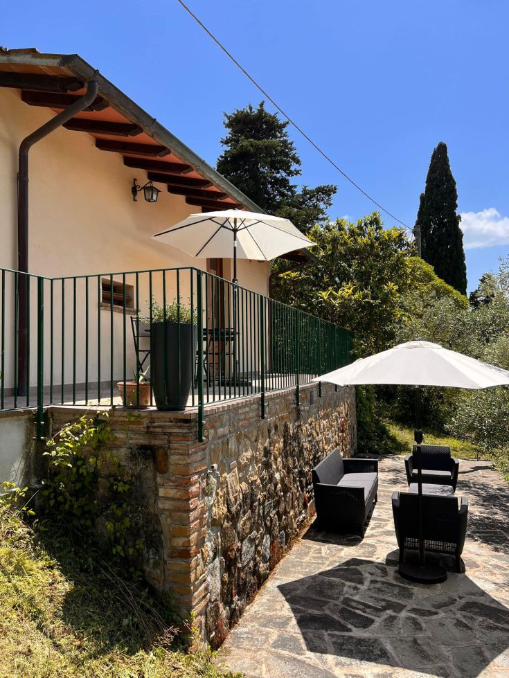 A farmhouse in Umbria surrounded by nature, featuring a terrace and umbrellas for outdoor relaxation.