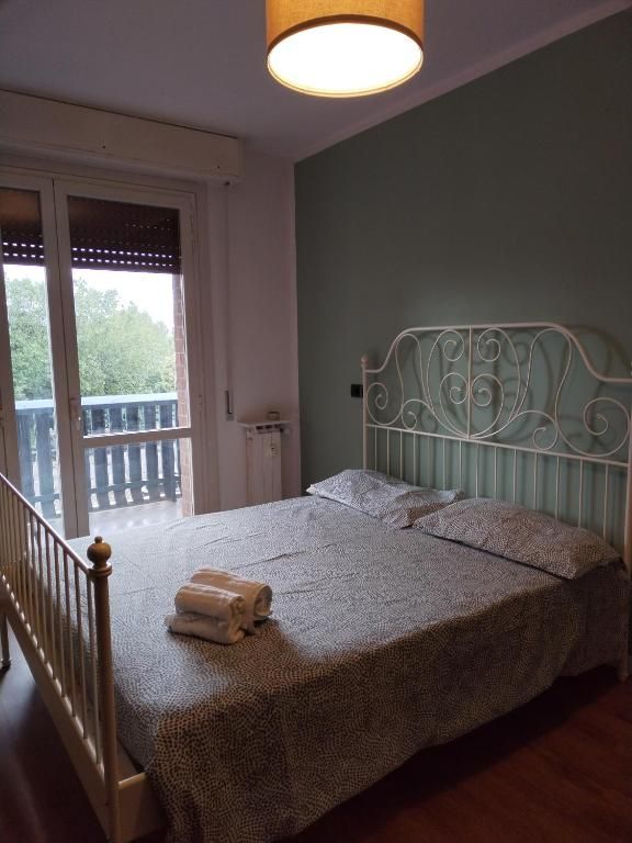 Camera semplice con letto matrimoniale e asciugamani, dotata di un balcone con vista su un'area verde.