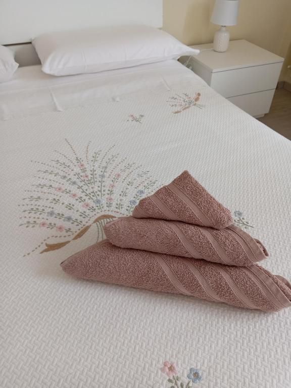 Letto ben rifatto con asciugamani piegati e fiori decorativi, per un ambiente accogliente e rilassante.