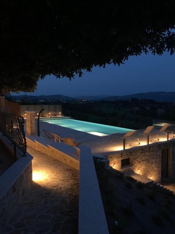 Une piscine extérieure illuminée dans un agritourisme entouré de verdure, idéale pour des moments de détente.