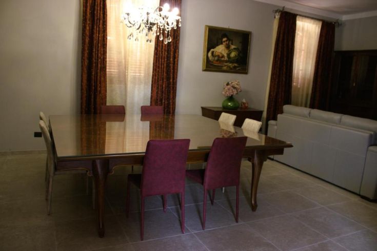 Un salon accueillant avec une grande table à manger et des fauteuils colorés, meublé de manière confortable.