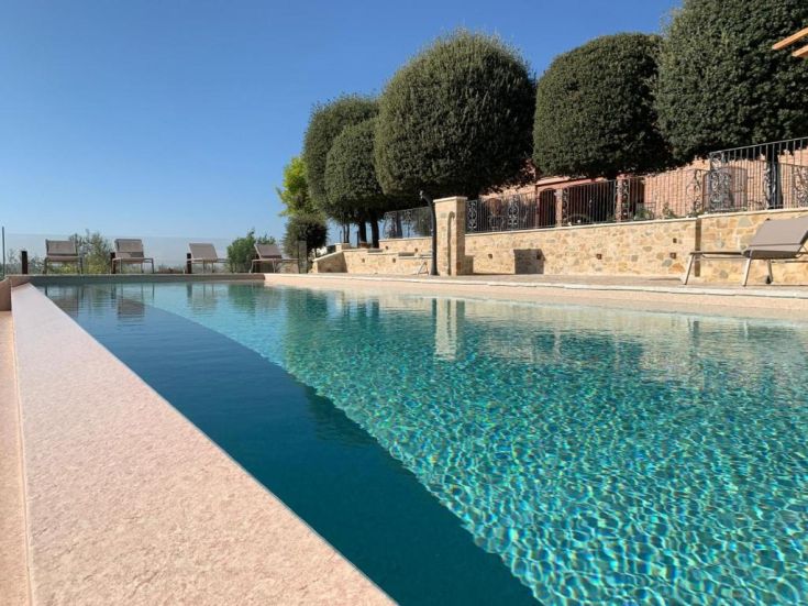 Piscine extérieure entourée d'arbres et de haies, idéale pour des moments de détente et de plaisir.