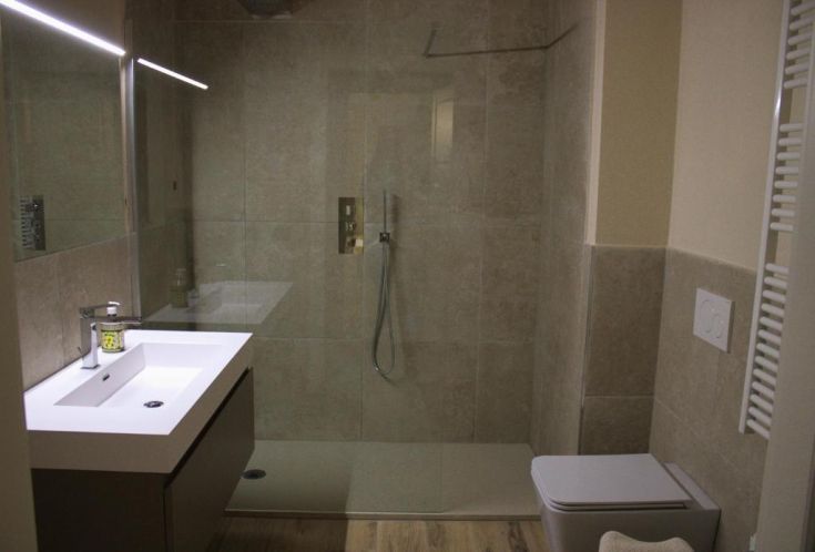 Salle de bain moderne avec douche, lavabo et éclairage doux. Design simple et fonctionnel, adapté à divers besoins.