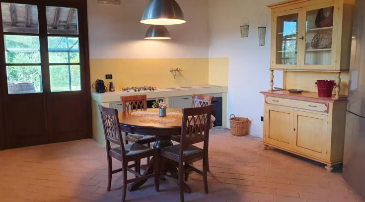 Bright and welcoming kitchen in a farmhouse, featuring a dining table with a view of the surrounding nature.