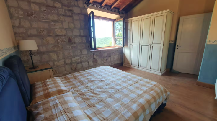 Cozy room with a double bed, stone walls, and a view of the garden.