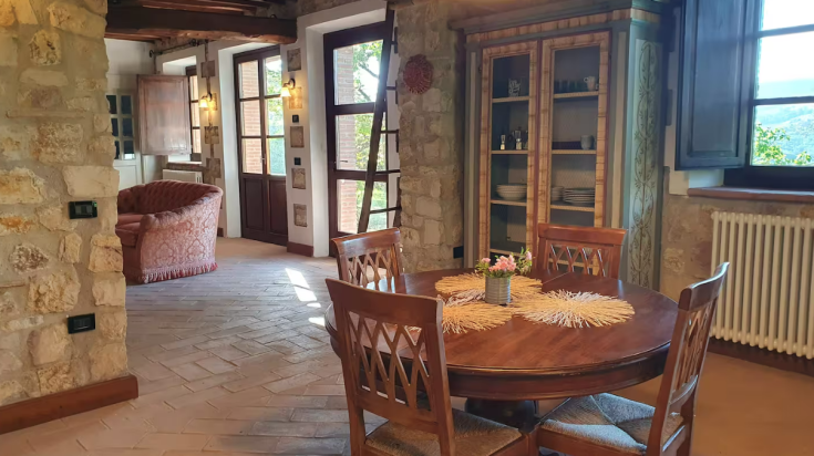 Inside a cottage featuring stone walls, a wooden table, and simple decorative details.