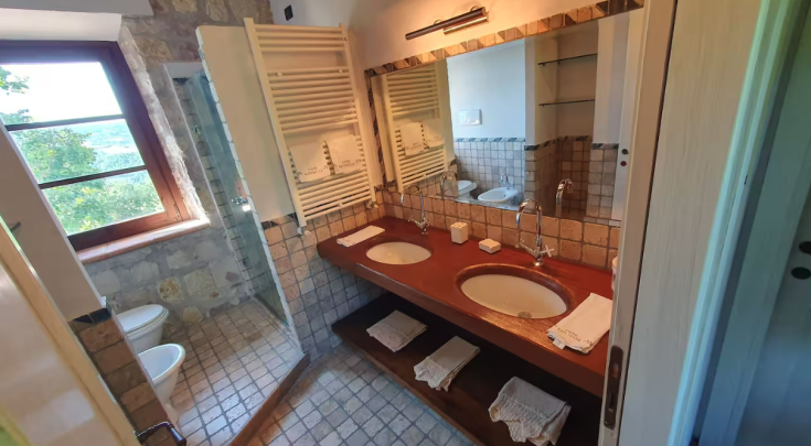 Elegant bathroom with double sink, overlooking a bright and welcoming green garden.