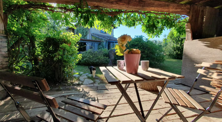 A cozy outdoor space featuring a table and chairs, surrounded by lush plants and vibrant flowers.