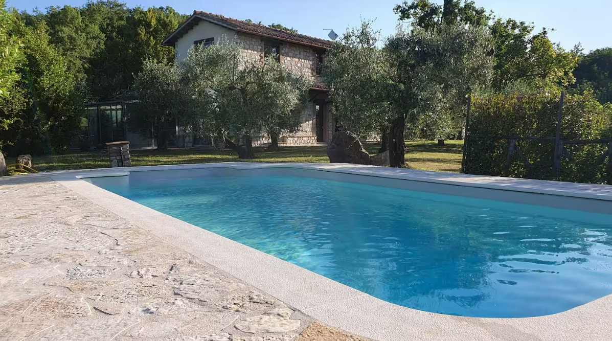 Cottage con piscina privata circondato da un ampio giardino verde.