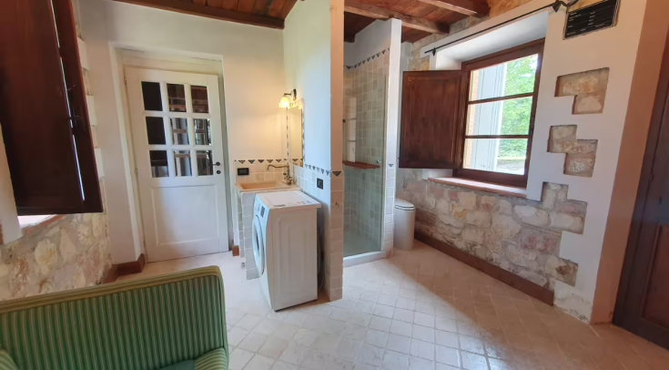 A simple cottage bathroom featuring a washing machine and shower; a space for relaxation.