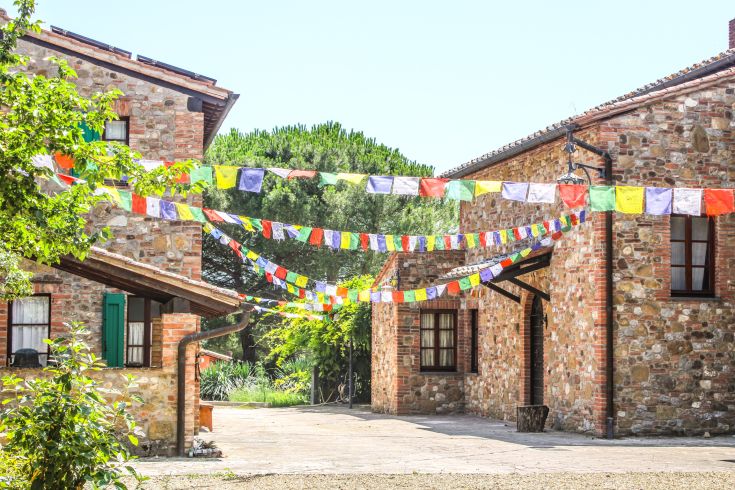 A peaceful rural property surrounded by a garden, featuring stone buildings and simple decorations.