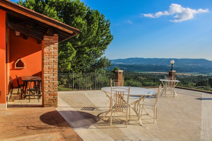 Outdoor space with tables, surrounded by hills and olive trees. A peaceful place to enjoy nature.