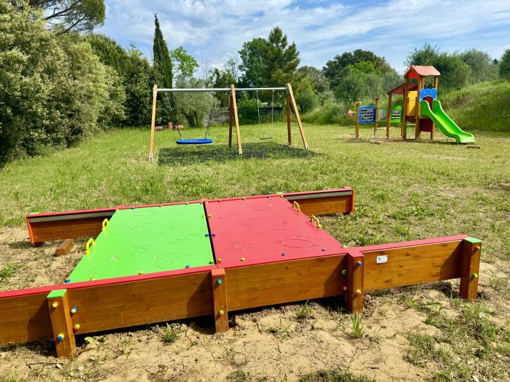 A playground surrounded by greenery, featuring swings and slides, perfect for children's fun.