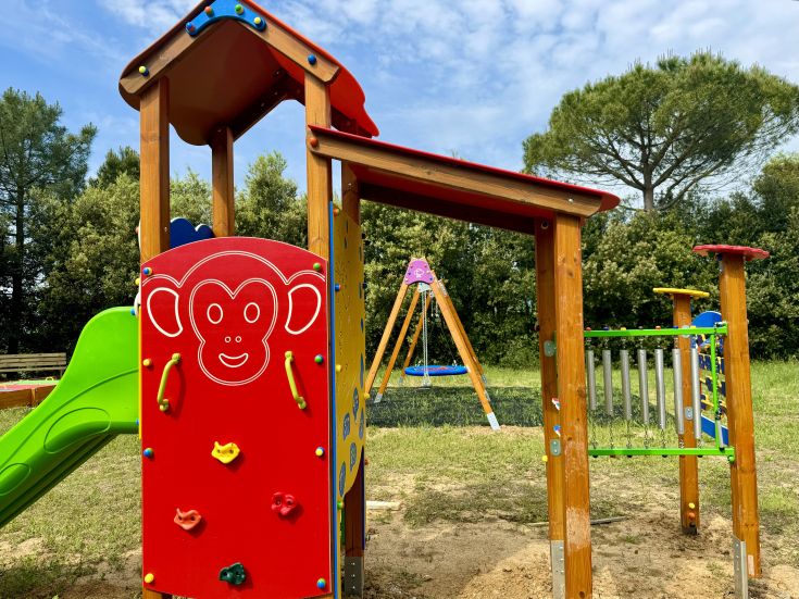 A lively and well-equipped play area surrounded by green trees, perfect for families and children.