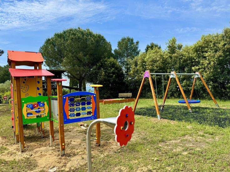 Colorful playground equipment in a park, surrounded by green trees, perfect for children's fun.