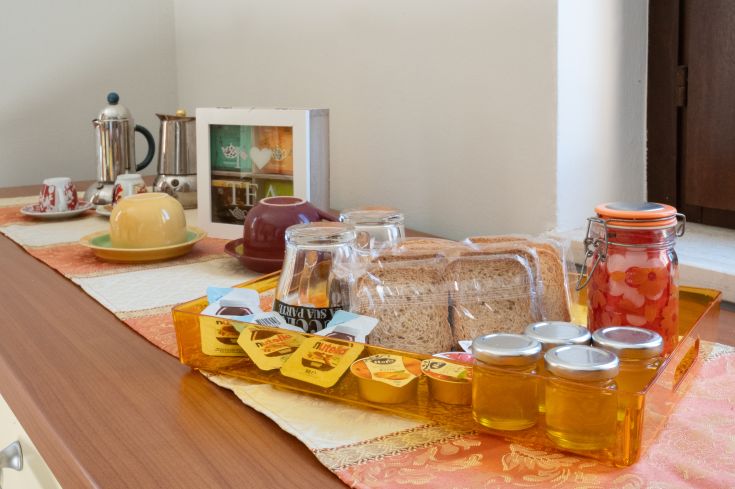 Una colazione servita con pane, varietà di confetture e caffè in un'atmosfera semplice e piacevole.