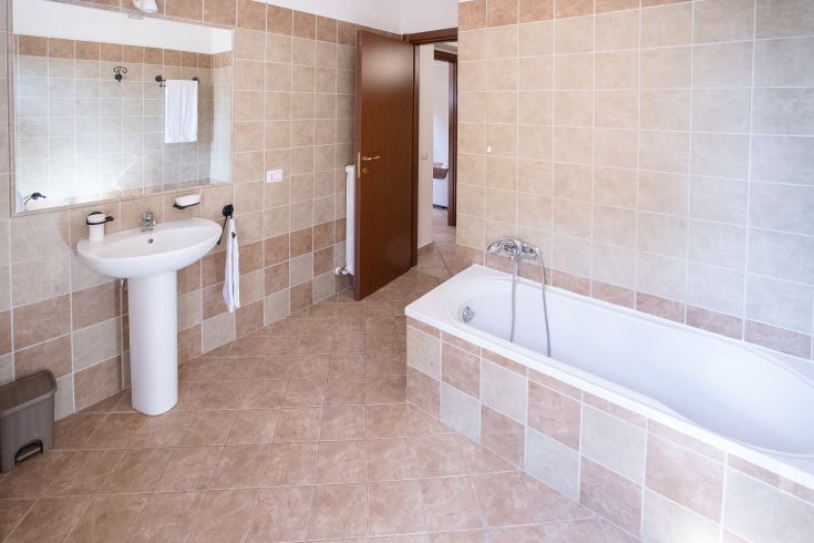 Ambiente moderno e ben illuminato con lavabo e vasca da bagno, arredato in modo semplice.