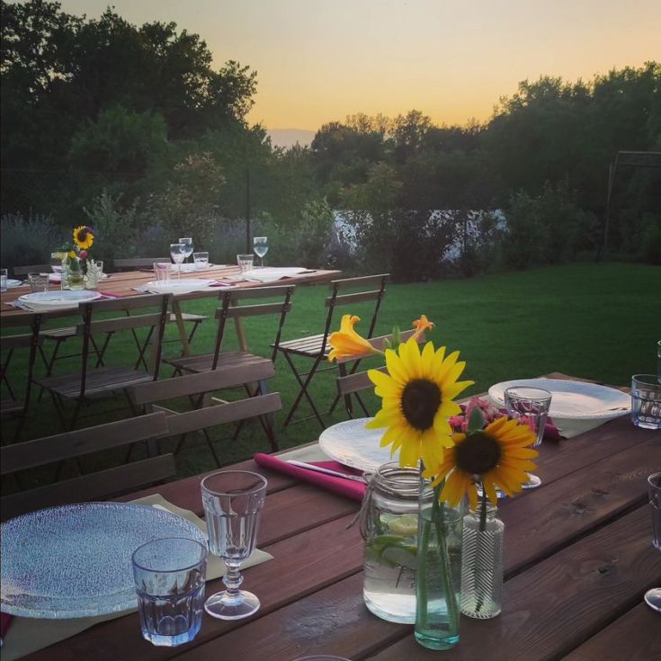 Una tavola con decorazioni floreali, allestita per una serata tranquilla in mezzo alla natura.