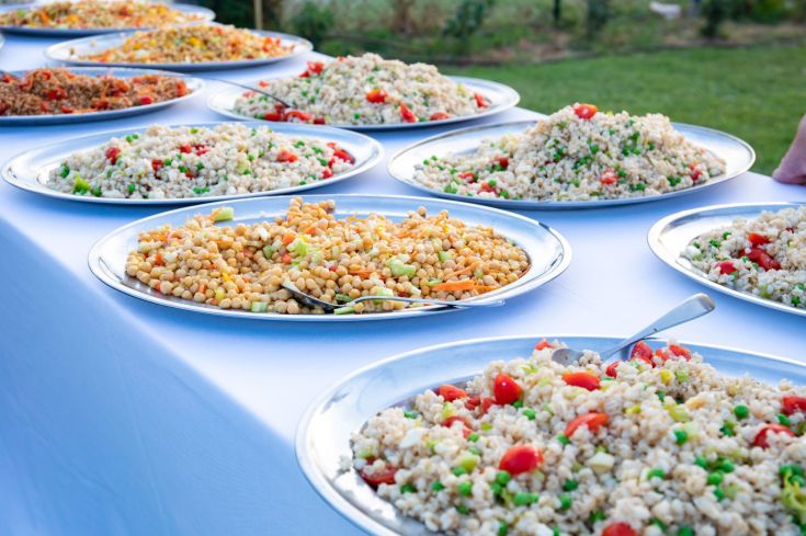 Un colpo d'occhio su un buffet con ciotole di cereali e verdure fresche disposto su un tavolo, ideale per eventi informali.