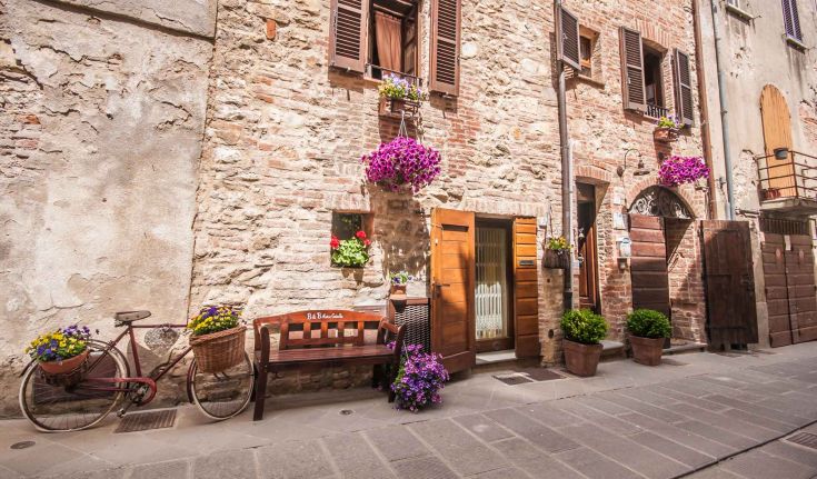 Eine ruhige Szene mit Blumen und einem alten Fahrrad in einer malerischen Ecke eines umbrischen Dorfes.