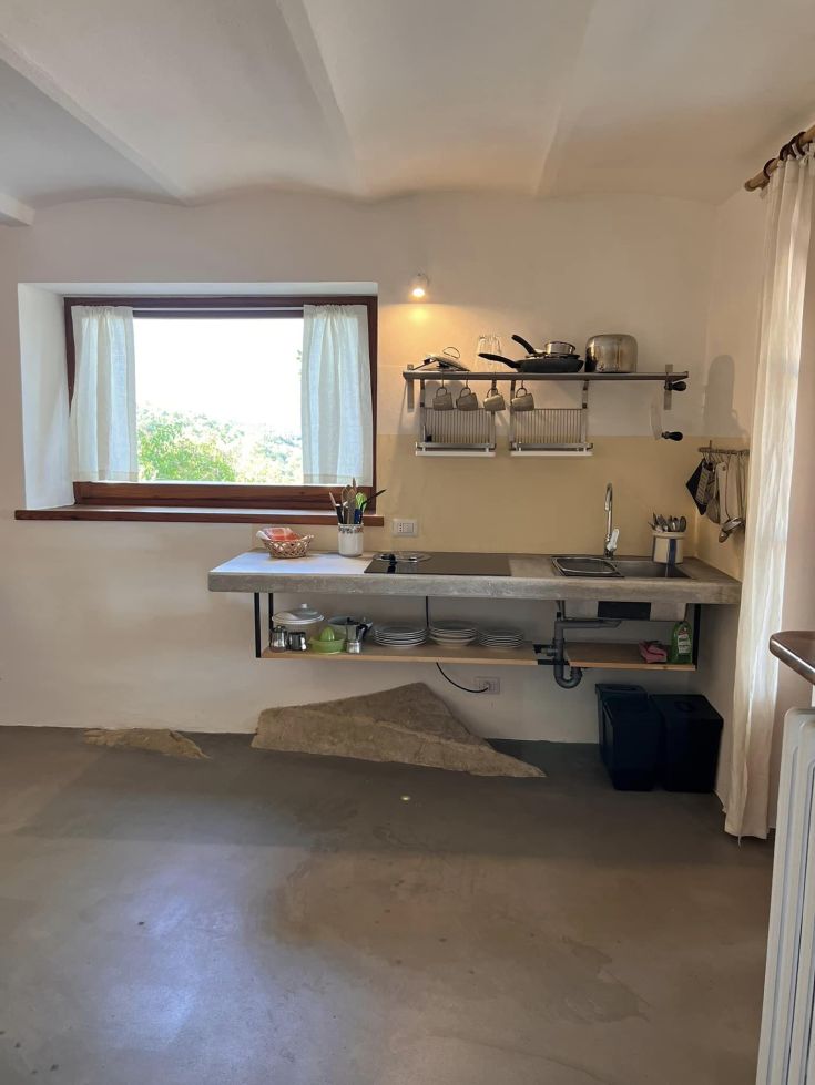 Cucina moderna e luminosa rivolta verso un'area verde, completa di piatti e utensili.