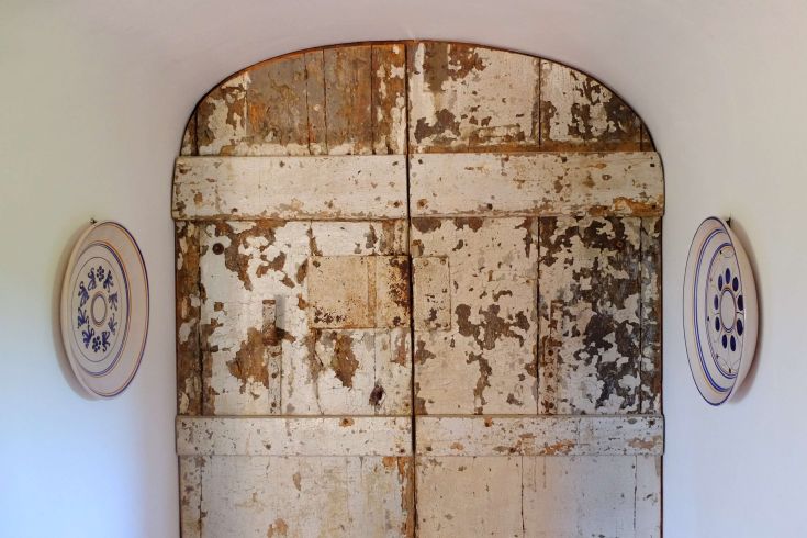 Porta di legno usurata in un interno sereno, decorata con piatti di ceramica. Ambiente semplice e accogliente.