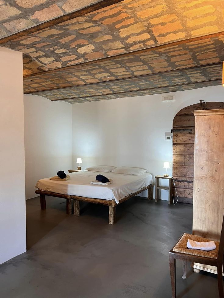Camera semplice con soffitto in pietra e particolari in legno, adatta per momenti di relax.