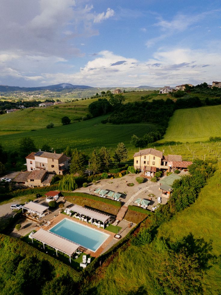 Una panoramica di Casale Serena, circondata da colline verdi e con una piscina ben curata.