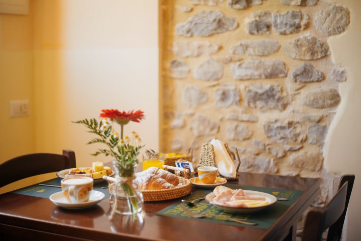 Un tavolo semplice è allestito per una colazione con dolci, frutta e bevande calde.