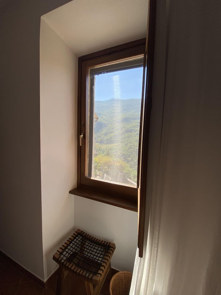 Ein gemütliches Zimmer mit einem Fenster, das einen Bergpanorama zeigt. Ein ruhiger Ort zum Entspannen.