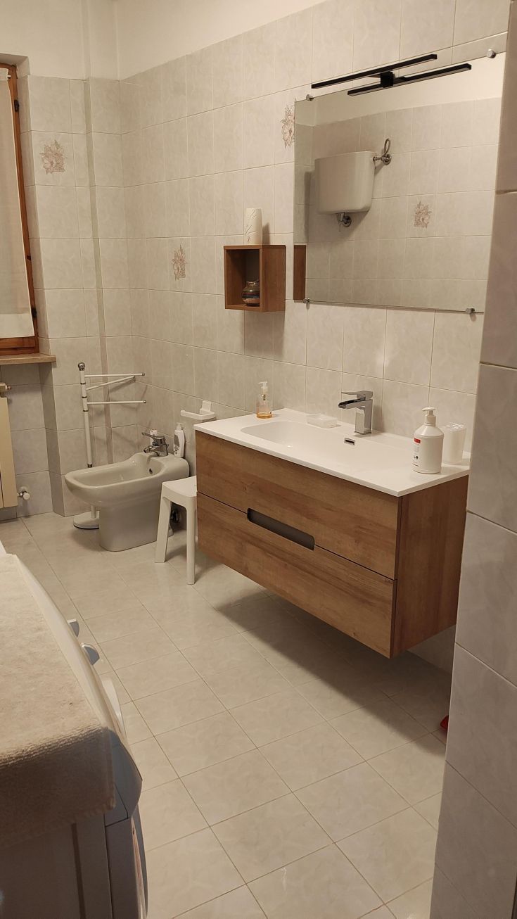 Modernes Badezimmer mit Holz-Möbeln und hellen Fliesen, ausgestattet mit einem Waschbecken und Bidet.