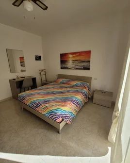 Einfache und helle Schlafzimmer mit einem dekorierten Bett, perfekt für entspannende Momente.