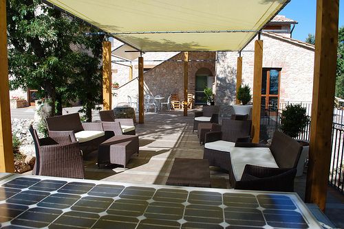 Bequemer Außenbereich mit Stühlen und Tischen, umgeben von Pflanzen und Bäumen.