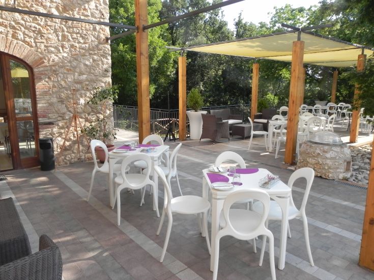Außenbereich eines Bauernhofs mit weißen Tischen und Blick auf eine natürliche Landschaft.