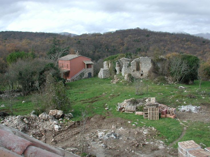 Ein Landgut umgeben von Grün, mit einem Hauptgebäude und Ruinen antiker Strukturen in der Nähe.