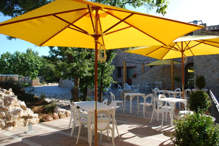 Ein Außenbereich mit gelben Sonnenschirmen und weißen Tischen, perfekt für entspannende Momente.