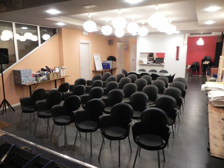 Veranstaltungsraum mit schwarzen Stühlen, beleuchtet von modernen Designleuchten.